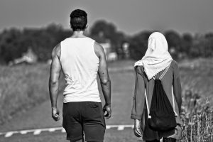 Muslimische Frau mit Kopftuch ist mit Europäer, Christ zusammen