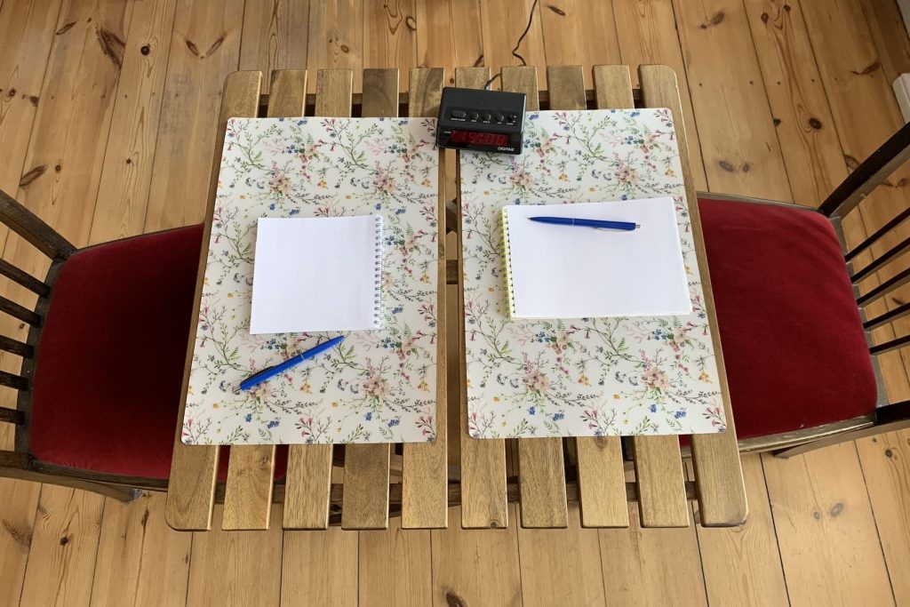 Geordnetes Paargespräch, Setting: Tisch, Wecker, Papier, Stift